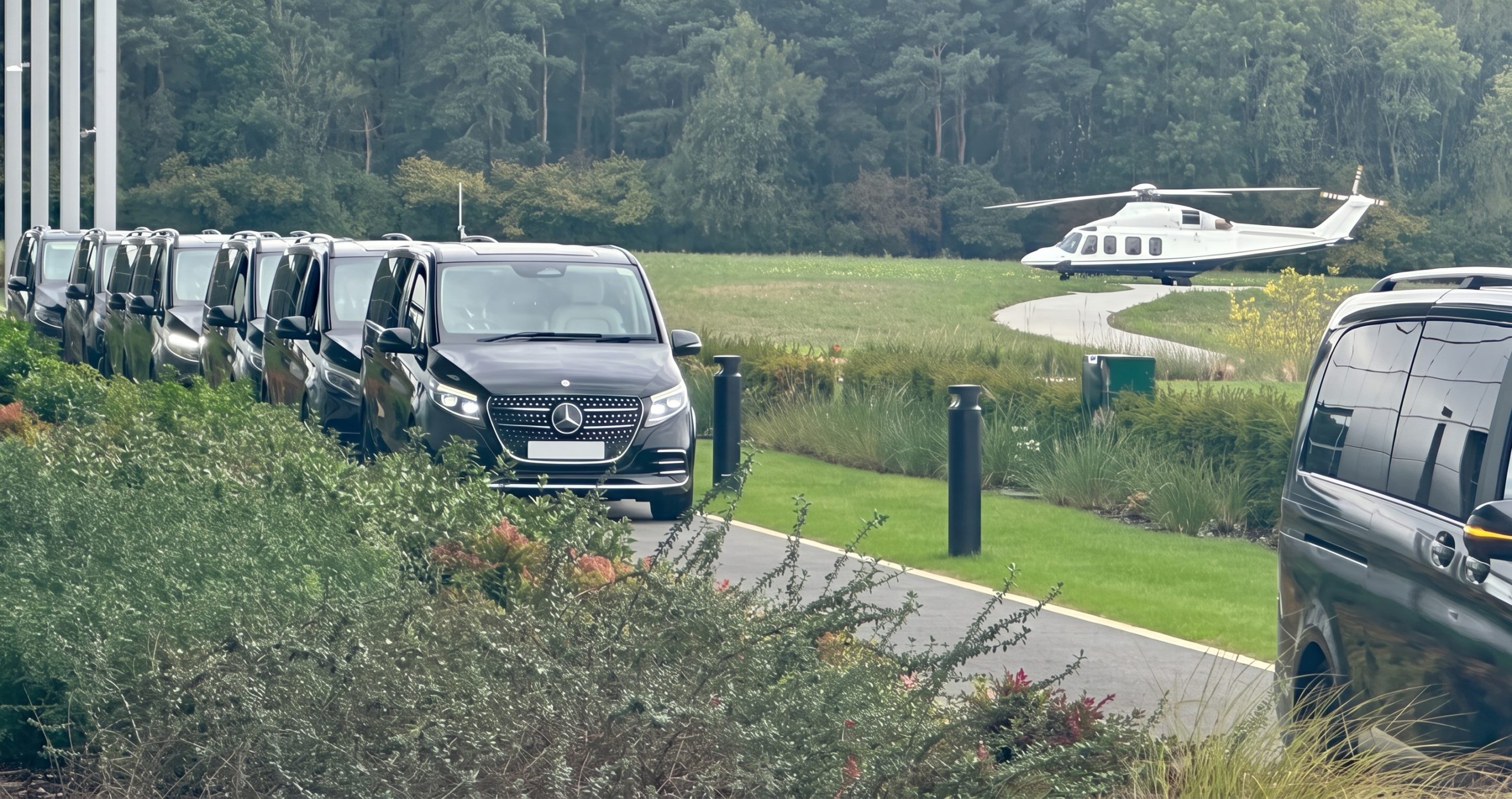 A line of black vans staged on a private drive, a helicopter waiting on the lawn beyond